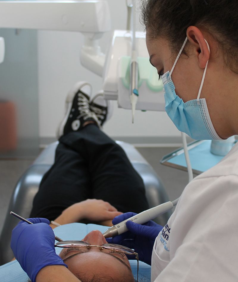 Higienista realizando un tratamiento periodoncia a un paciente.
